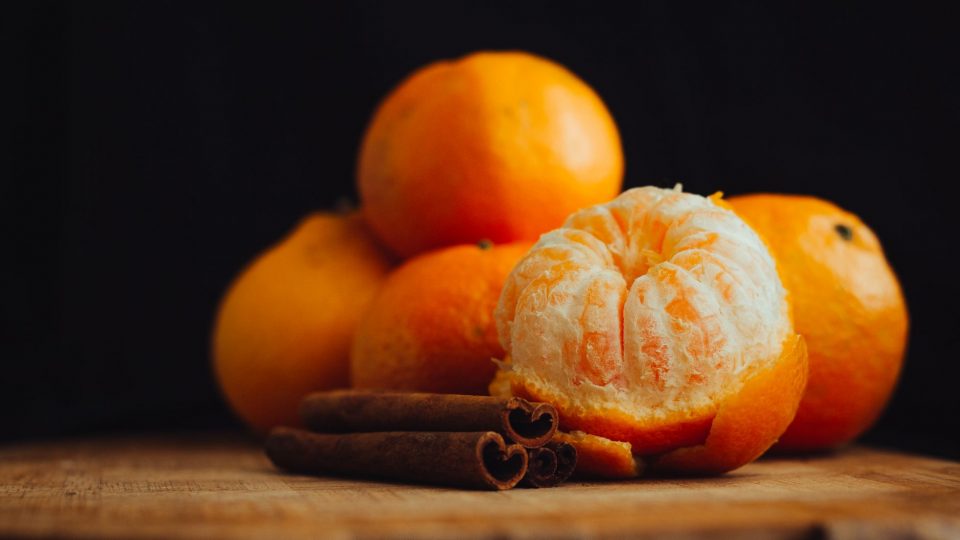 A close-up of fresh peeled tangerines with cinnamon sticks, creating a warm, inviting mood.
